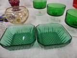 two green glass bowls sitting on a table next to other glassware
