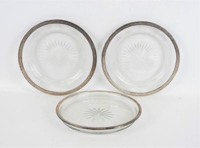trois assiettes en verre à bordure argentée sont posées sur une surface blanche