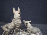 two statues of a dog and a cat sitting on a rock