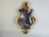 a gold and purple mirror hanging on the wall