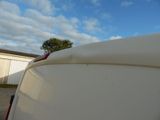 a white surfboard sitting on top of the roof of a white van