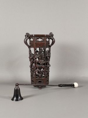 un petit vase en bois avec une clochette posé sur une table