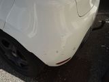 a white car that has been dented and is parked in a parking lot