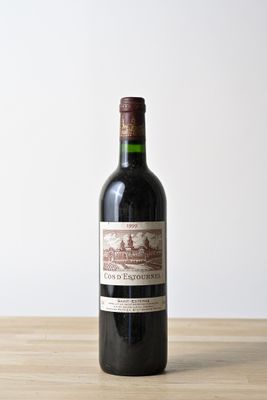 une bouteille de vin rouge posée sur une table en bois, avec un mur blanc en arrière-plan