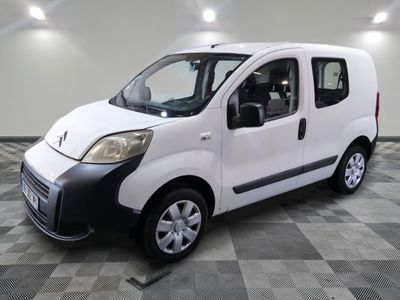 la petite camionnette blanche est garée sur un carrelage à carreaux