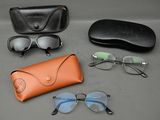 des lunettes de soleil, un étui à lunettes de soleil et des lunettes posées sur une table à côté d'une paire de lunettes