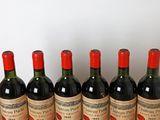 six bouteilles de vin rouge sont alignées sur une table en bois