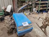 un tracteur bleu garé dans un garage, sur lequel est accrochée une pancarte