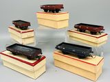six wagons de train miniature exposés sur des socles en bois
