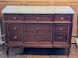 une commode en bois avec un plateau en marbre posée sur un parquet en bois massif