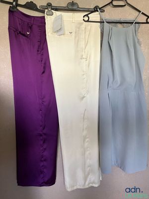 trois paires de pantalons suspendues à un portant devant un mur