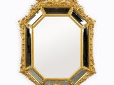 un miroir doré richement décoré, bordé d'une moulure noire et blanche