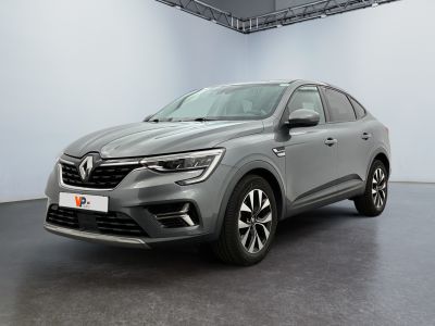 Une voiture grise est garée dans une pièce aux murs blancs.