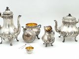 a silver tea set on a white background with a gold bowl