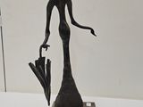 statue d'une femme avec un chapeau et un parapluie posés sur une table