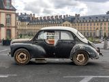 an old car parked in a parking lot in front of a building