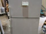 a white refrigerator with a sticker on it in a warehouse