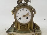 a clock with two birds on it sitting on a table