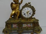 a gold clock with an angel on top of it