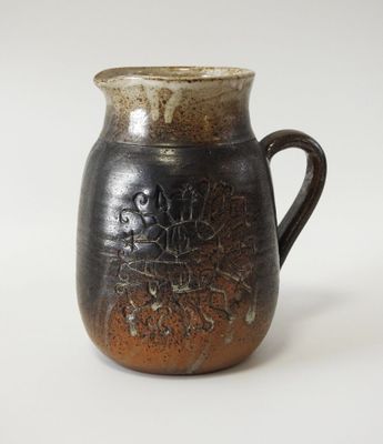 une tasse noire et marron avec une anse, posée sur une surface blanche