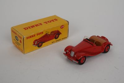 une petite voiture rouge devant une boîte, posée sur une surface blanche