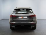 the rear end of a grey car in a white room