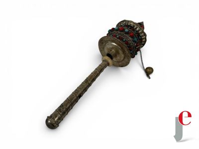 a small metal object with a long handle on a white surface