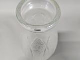 a glass jar with a liquid inside of it on a white surface