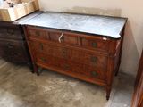 a dresser with a marble top next to a chest of drawers