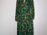 La robe est verte et orange, avec des motifs de feuilles dessus.