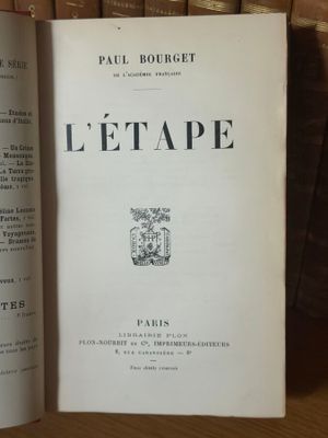 un livre ouvert posé sur une table en bois, à côté d'une pile de livres