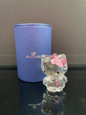 une figurine Hello Kitty posée sur une table à côté d'une tasse