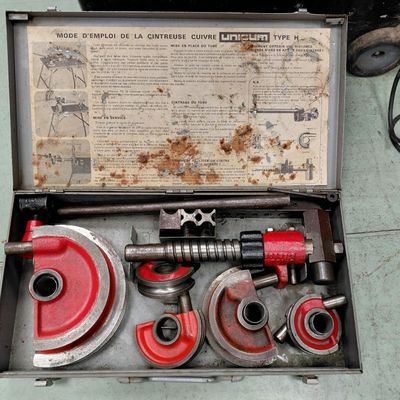 une mallette métallique posée par terre, contenant des outils