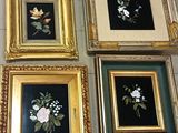 quatre tableaux représentant des fleurs, encadrés, sont exposés sur un sol carrelé