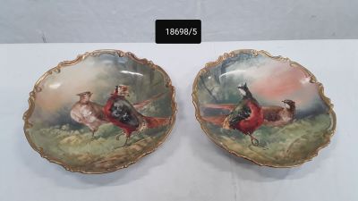 deux assiettes ornées de coqs, posées sur une table