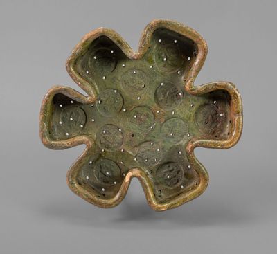 a close up of a green flower shaped bowl on a gray surface