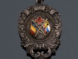 a close up of a silver medal with a cross and two flags on it