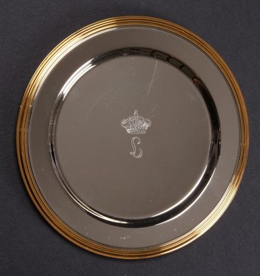 une assiette en argent bordée d'or et ornée d'une couronne