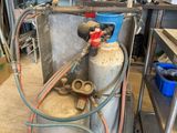 une bonbonne de propane à laquelle est raccordé un tuyau, dans un garage