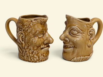 une paire de tasses en céramique marron ornées des visages de deux hommes et d'une femme