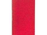 un livre rouge posé sur une table blanche à côté d'un mur blanc