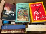many books in a box with a clock on top of them