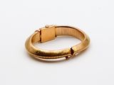 a close up of a gold bracelet on a white surface