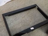 a black frame on the floor next to a white wall