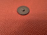 a close up of a metal button on a red cloth