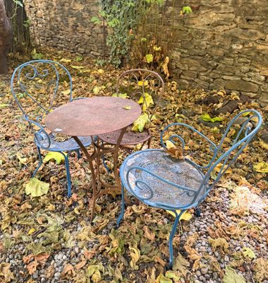 une petite table et des chaises au milieu des feuilles