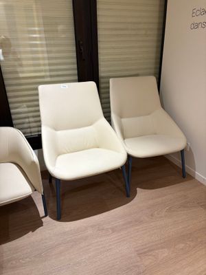 three white chairs in a waiting room next to a window