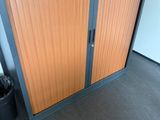 une armoire avec une porte et une poubelle à côté