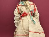 an old fashioned doll sitting on a chair against a red background