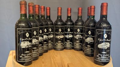 six bottles of red wine are lined up on a wooden barrel